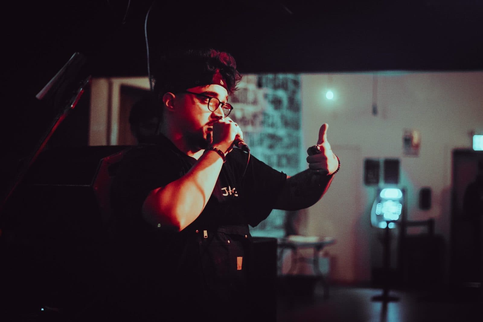 Performer speaking into a microphone and giving a thumbs-up from the stage